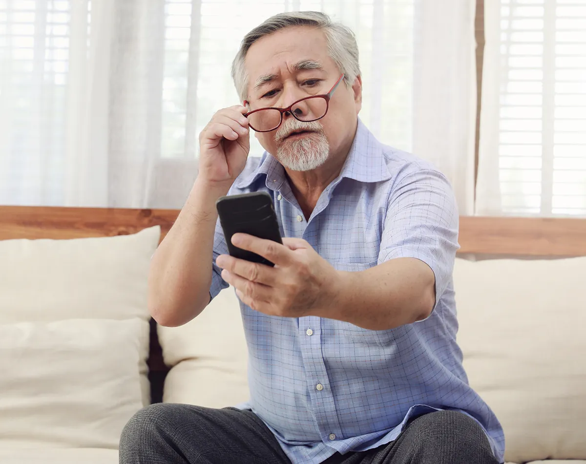 mature man struggling to read his phone close up