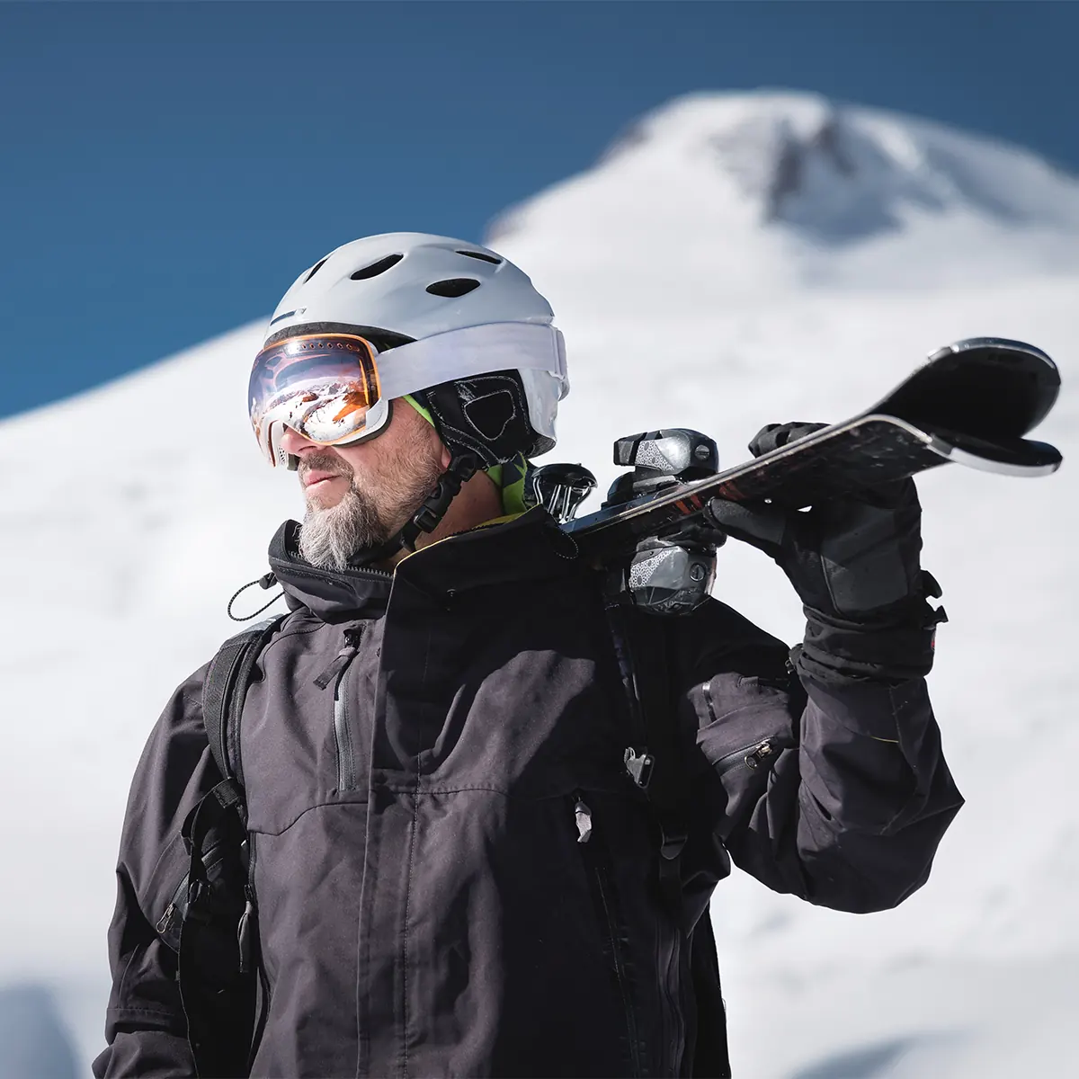 man on snowy slope holding skis