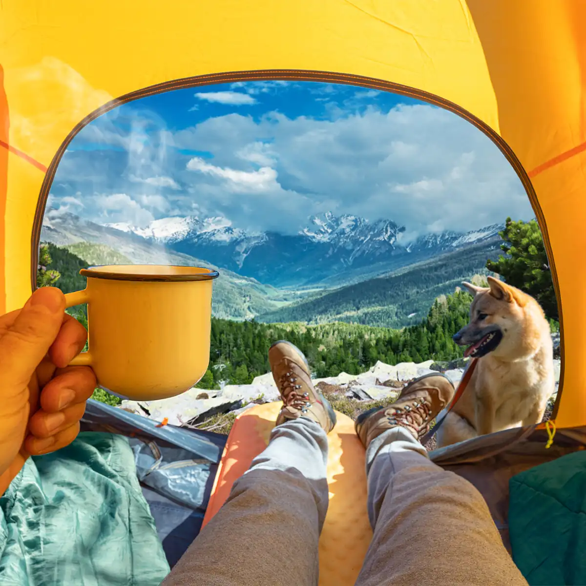 man holding cup of coffee enjoying mountain view from tent