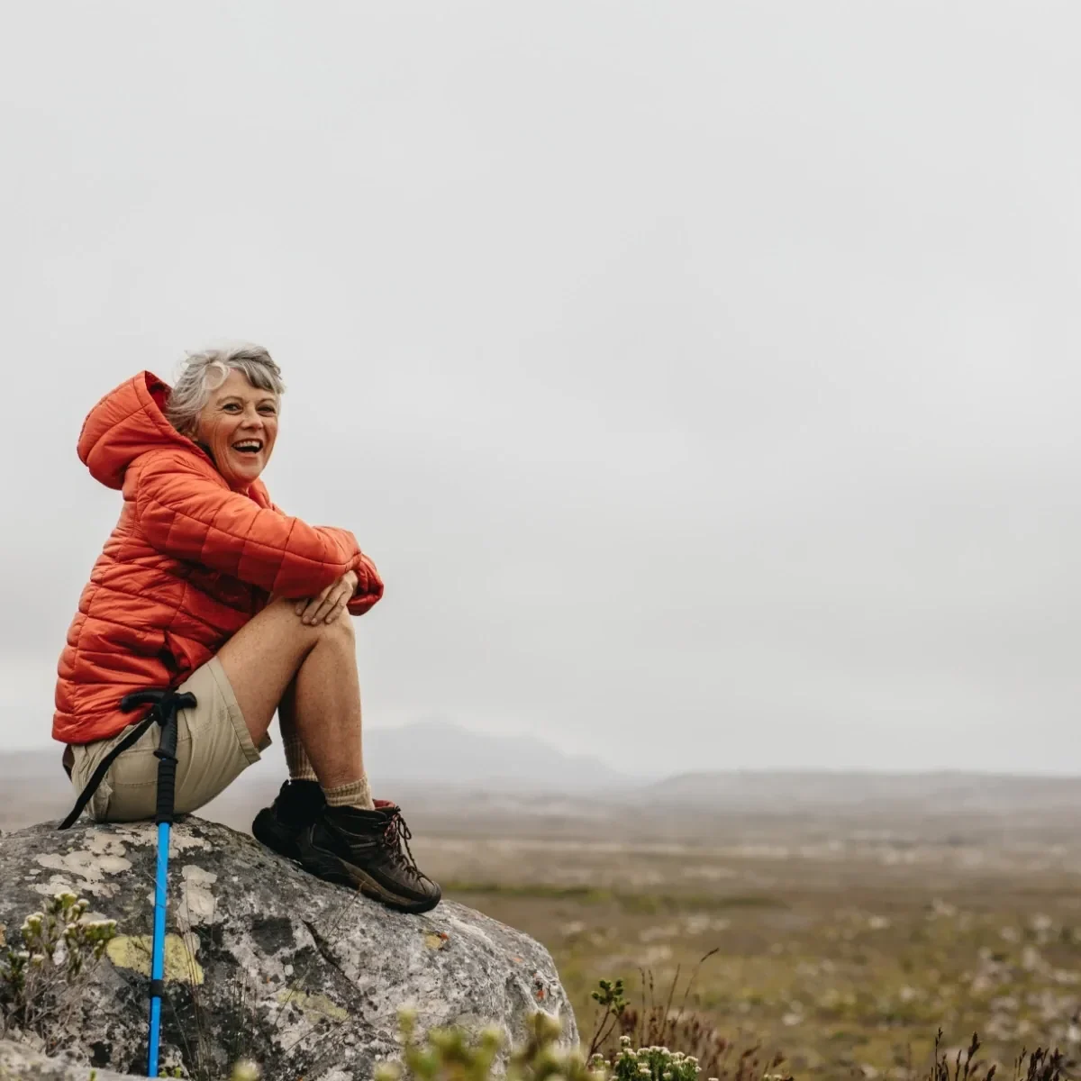 older hiker sitting on rock and smiling