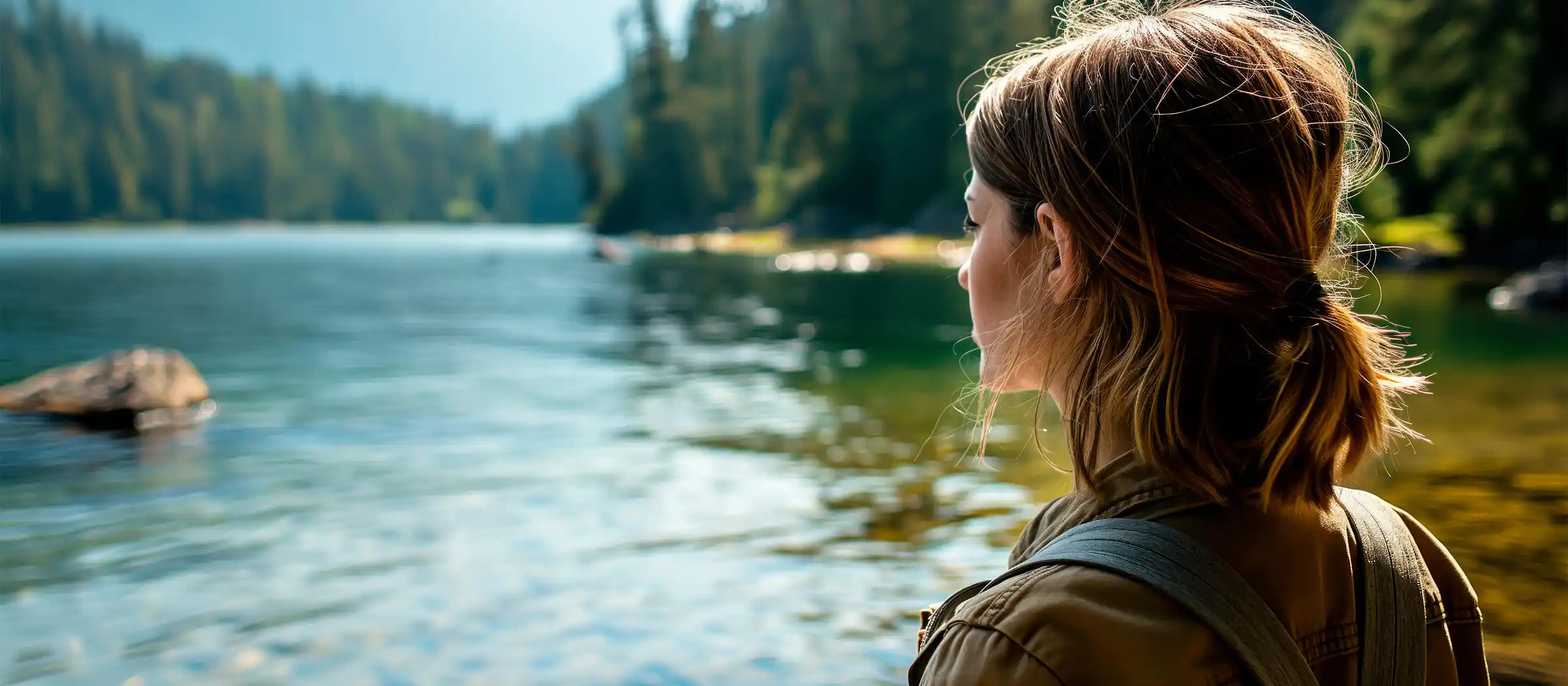 young female hiker admiring the clear water in the lake